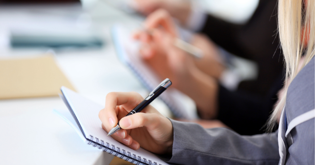 Woman holds pen and notebooks and prepares to write something down