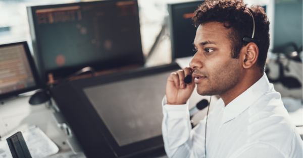 A man sits in front of a monitor wearing a headset.