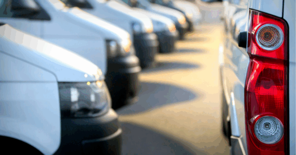 A row of white vans on the left side of the image. On the right side is the back/bottom left side of another white van